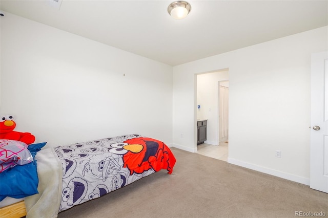 bedroom featuring light carpet and ensuite bath