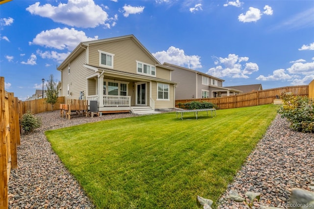 back of house featuring a yard and a trampoline