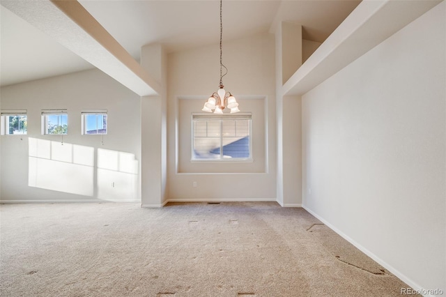 carpeted empty room featuring a chandelier and high vaulted ceiling