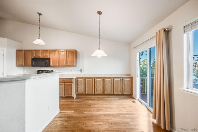 kitchen with decorative light fixtures, vaulted ceiling, and light hardwood / wood-style flooring