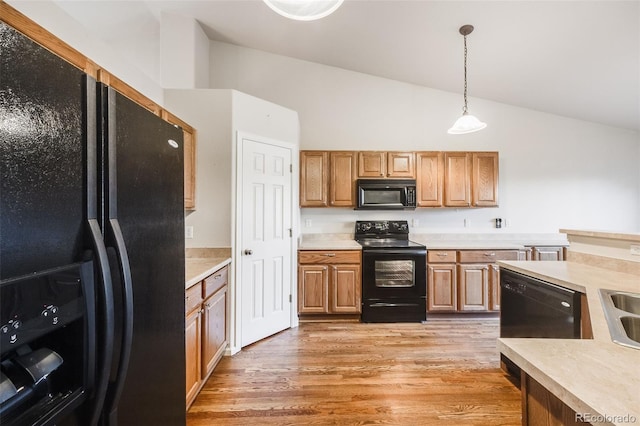 kitchen featuring pendant lighting, high vaulted ceiling, sink, black appliances, and light hardwood / wood-style flooring