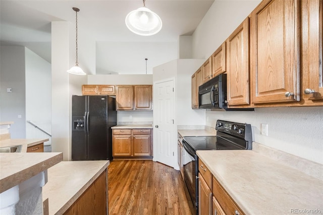 kitchen featuring hanging light fixtures, dark wood-type flooring, and black appliances