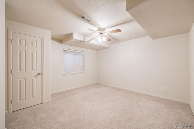 spare room with light carpet, ceiling fan, and a textured ceiling