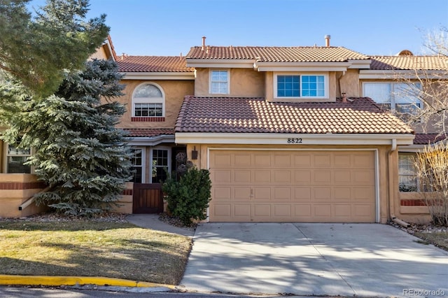 mediterranean / spanish-style house featuring a garage, concrete driveway, a tiled roof, and stucco siding