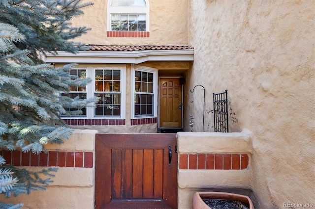 doorway to property with a tiled roof and stucco siding