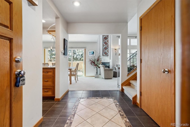 entrance foyer with stairway, baseboards, and dark tile patterned floors