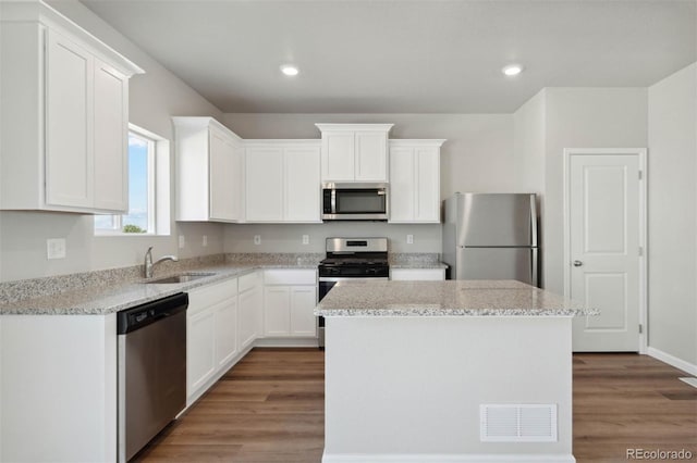 7303 Dolores Ave, Frederick, CO 80530 - kitchen featuring stainless steel appliances, a sink, a kitchen island, wood finished floors, and white cabinets