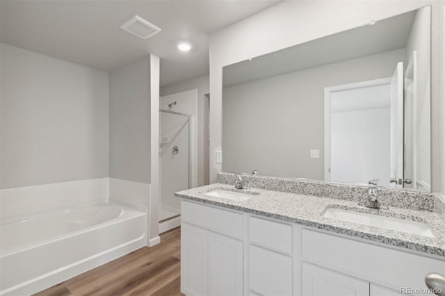 7303 Dolores Ave, Frederick, CO 80530 - bathroom featuring a shower stall, wood finished floors, a bath, double vanity, and recessed lighting