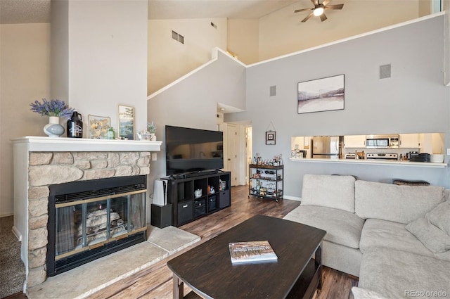 3600 S Pierce St Unit 1-207, Denver, CO 80235 - living room with high vaulted ceiling, ceiling fan, wood finished floors, a stone fireplace, and baseboards