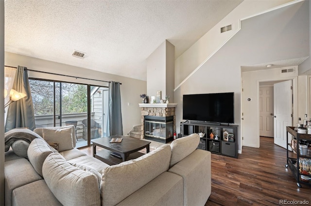 3600 S Pierce St Unit 1-207, Denver, CO 80235 - living area with dark wood-style flooring, a textured ceiling, a stone fireplace, and high vaulted ceiling