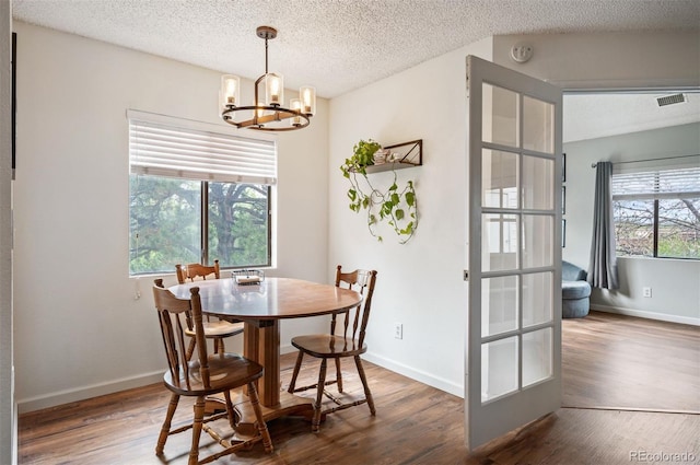 3600 S Pierce St Unit 1-207, Denver, CO 80235 - dining area featuring a chandelier, wood finished floors, a textured ceiling, and baseboards