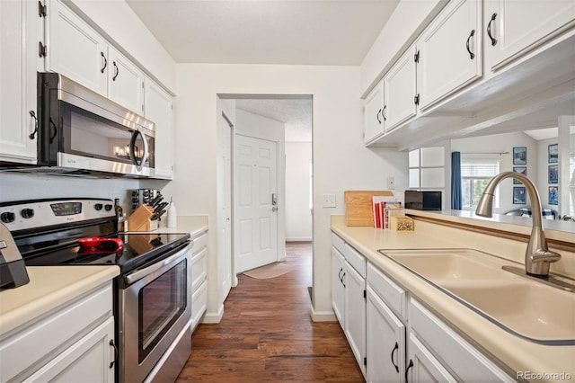 3600 S Pierce St Unit 1-207, Denver, CO 80235 - kitchen featuring stainless steel appliances, a sink, white cabinetry, light countertops, and dark wood finished floors