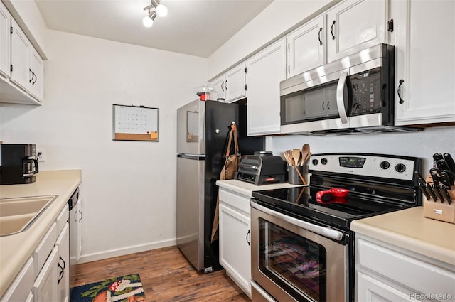 3600 S Pierce St Unit 1-207, Denver, CO 80235 - kitchen featuring appliances with stainless steel finishes, baseboards, wood finished floors, and white cabinets