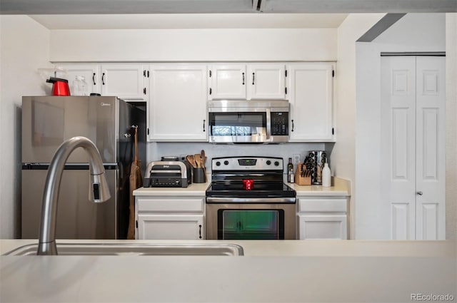 3600 S Pierce St Unit 1-207, Denver, CO 80235 - kitchen with appliances with stainless steel finishes, white cabinets, a sink, and light countertops