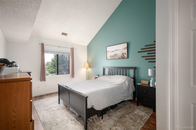 3600 S Pierce St Unit 1-207, Denver, CO 80235 - bedroom featuring wood finished floors, a textured ceiling, lofted ceiling, and baseboards