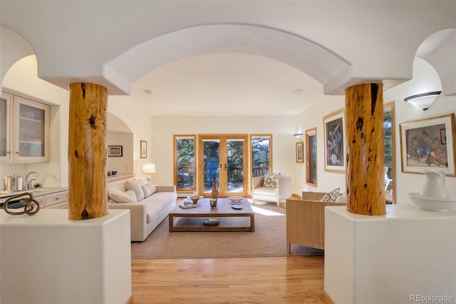 living room featuring decorative columns, light wood-type flooring, and french doors