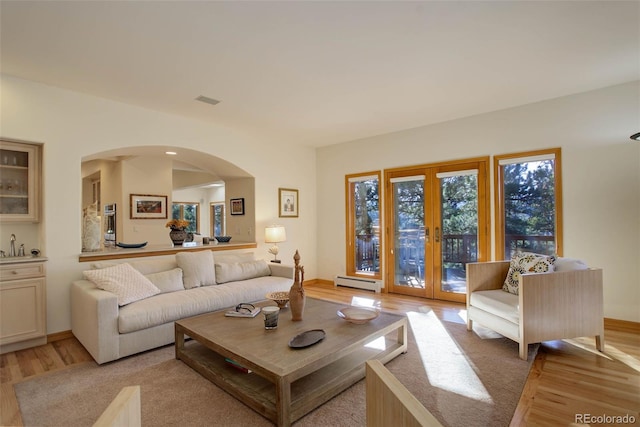 living room featuring light hardwood / wood-style flooring, baseboard heating, and french doors