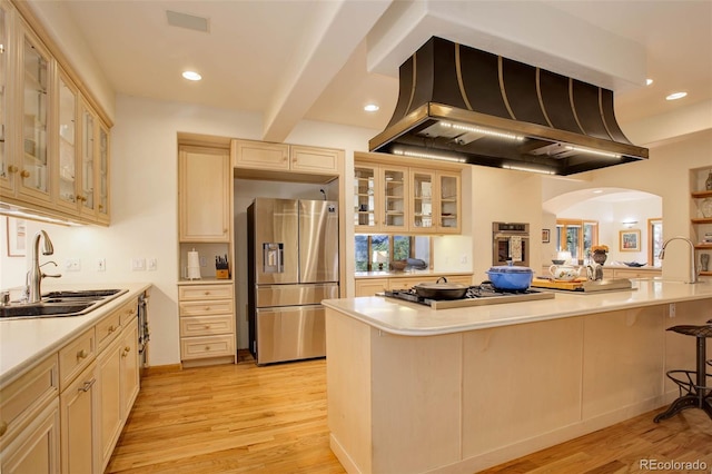 kitchen featuring stainless steel appliances, island exhaust hood, beam ceiling, a breakfast bar area, and sink