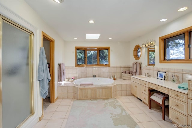 bathroom with a relaxing tiled tub, a skylight, tile patterned flooring, and vanity