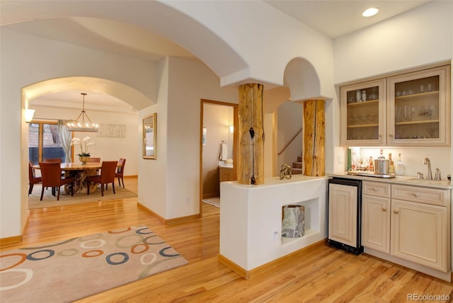 kitchen featuring decorative light fixtures, light wood-type flooring, a notable chandelier, and sink