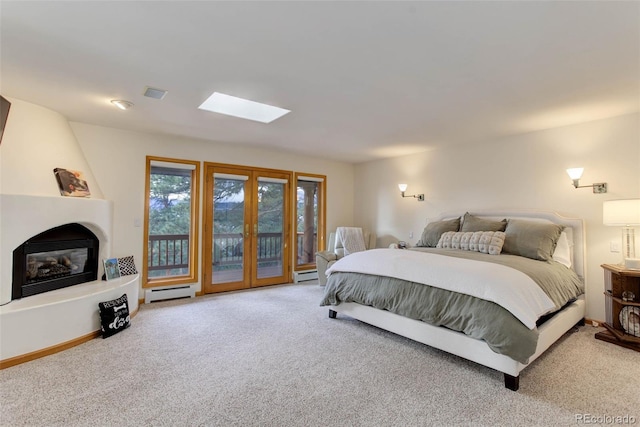 carpeted bedroom featuring a large fireplace, baseboard heating, a skylight, and access to exterior