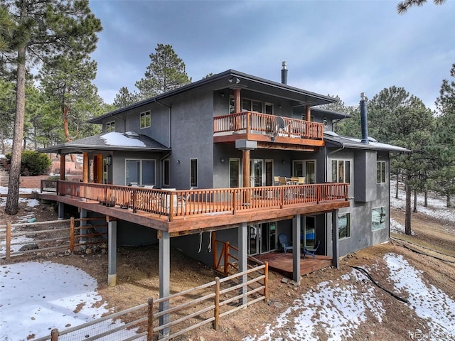 snow covered property featuring a balcony and a deck