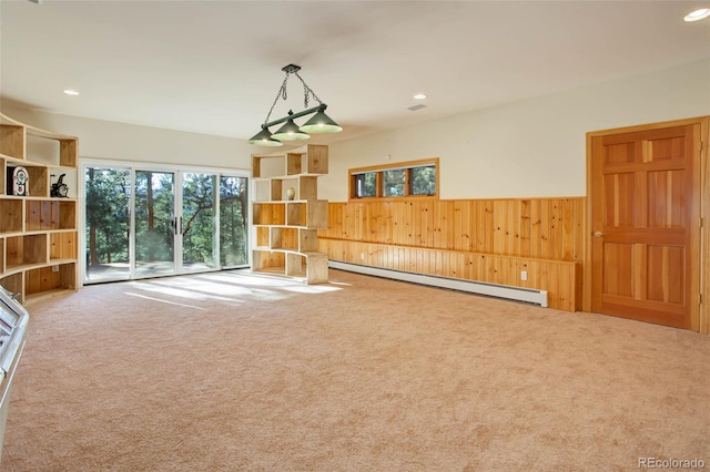 living room with baseboard heating, wooden walls, and carpet floors