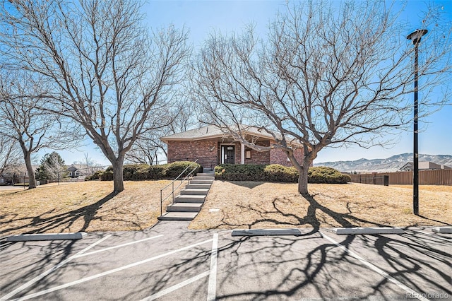 view of front of property featuring brick siding, fence, and a mountain view