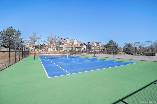 view of tennis court with a residential view and fence