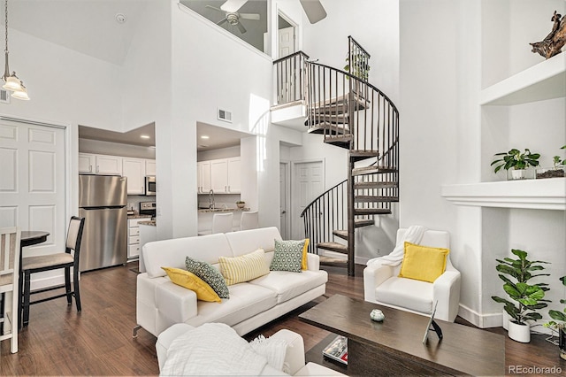 living area with baseboards, visible vents, a ceiling fan, dark wood-style floors, and stairs