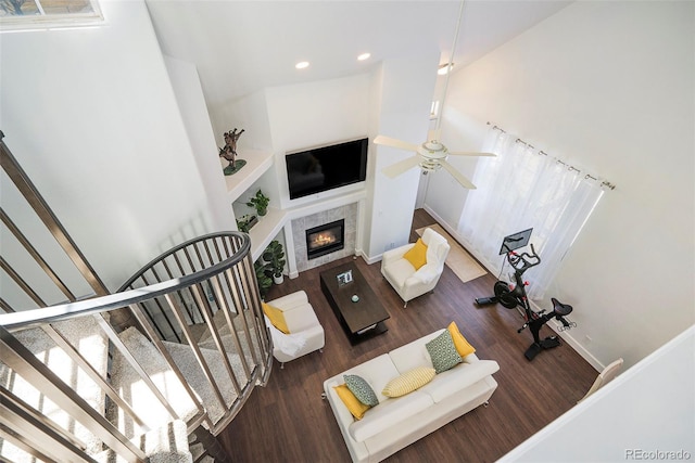 living room featuring stairway, a tiled fireplace, ceiling fan, wood finished floors, and baseboards