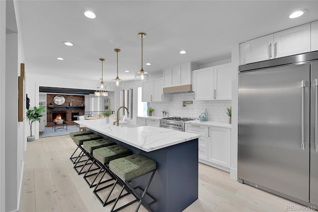 kitchen featuring white cabinets, a kitchen island with sink, sink, and premium appliances