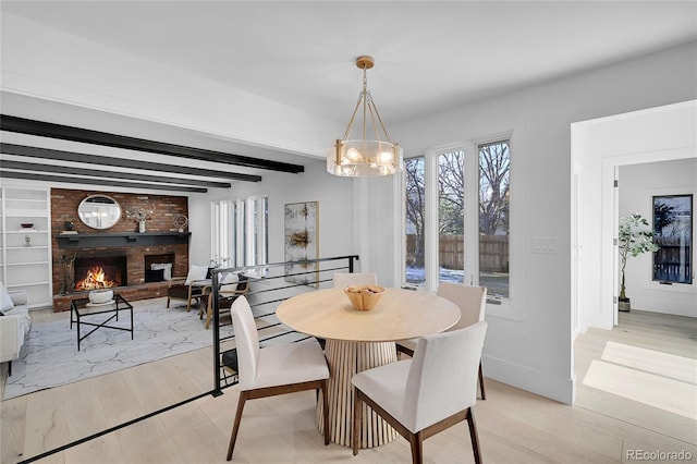 dining space with beam ceiling, light hardwood / wood-style floors, and a fireplace