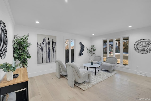 living room with ornamental molding and light hardwood / wood-style flooring