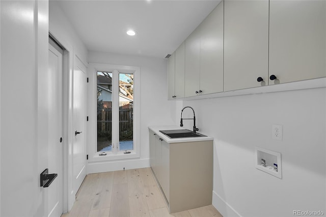 washroom with sink, light hardwood / wood-style floors, cabinets, and washer hookup