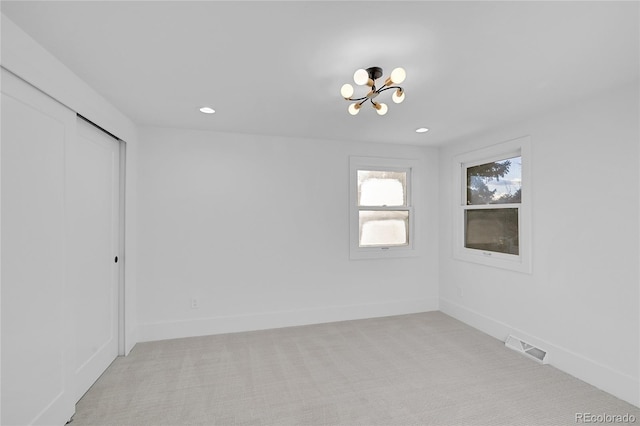 carpeted empty room featuring an inviting chandelier