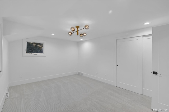 carpeted spare room with a chandelier and vaulted ceiling