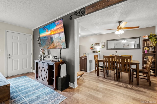 dining area with ceiling fan, a textured ceiling, and light wood-type flooring