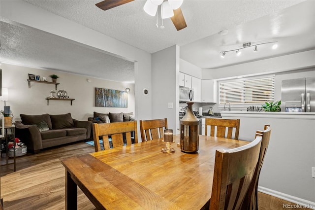 dining room with ceiling fan, light hardwood / wood-style flooring, and a textured ceiling