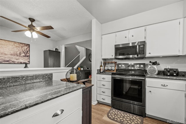 kitchen featuring white cabinetry, ceiling fan, stainless steel appliances, a textured ceiling, and light wood-type flooring