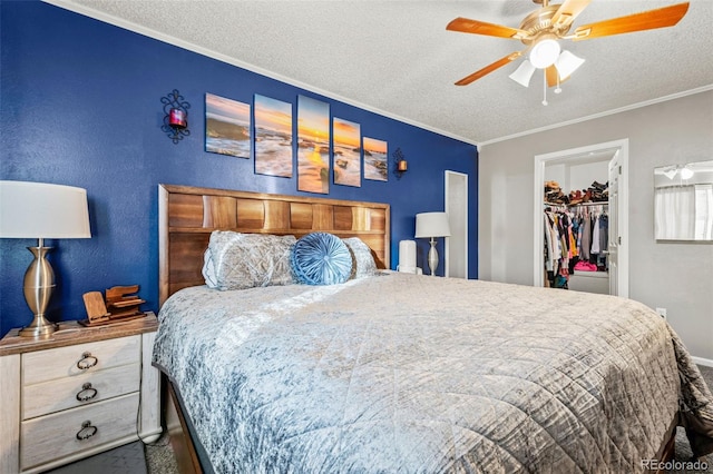 bedroom with crown molding, a walk in closet, a textured ceiling, a closet, and ceiling fan