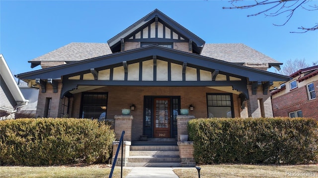 view of front of property with brick siding, roof with shingles, and a porch