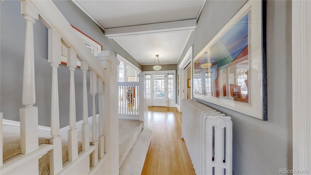 hallway featuring radiator, stairway, ornate columns, crown molding, and light wood-style floors