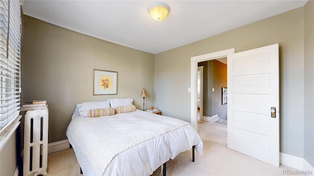 bedroom with radiator heating unit, baseboards, and light colored carpet