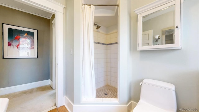 bathroom featuring toilet, a stall shower, and baseboards