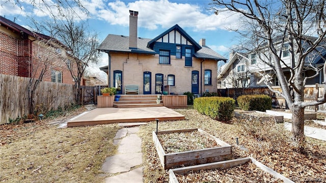 rear view of house with a shingled roof, a chimney, a fenced backyard, and a garden