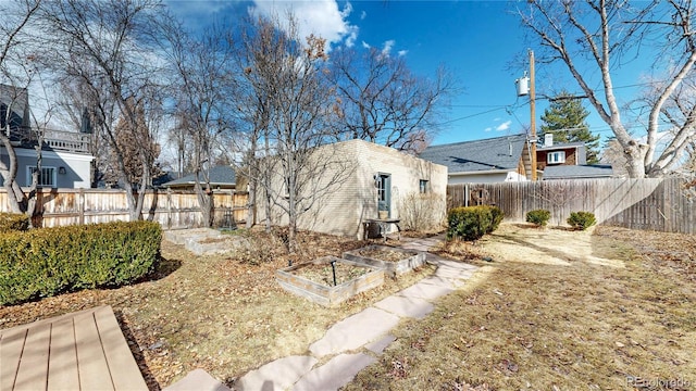 back of property featuring a garden, an outdoor structure, and a fenced backyard