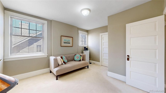 sitting room with radiator heating unit, light carpet, and baseboards