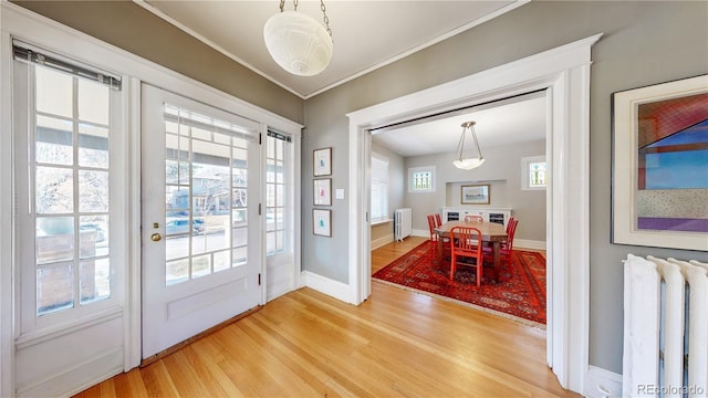 doorway with radiator, baseboards, light wood-style flooring, and radiator heating unit