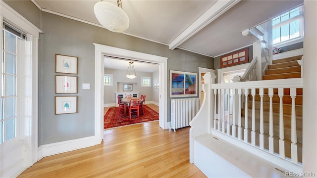 foyer entrance featuring baseboards, wood finished floors, stairs, crown molding, and beam ceiling